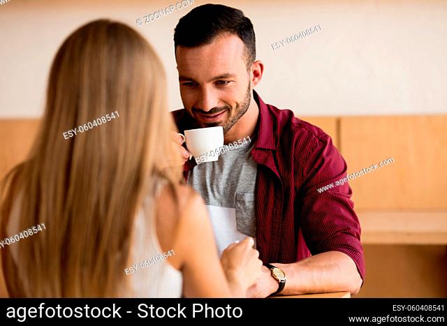 Beautiful Loving Couple Having Coffee In Cafe. Smiling To each Other. Love Story Concept