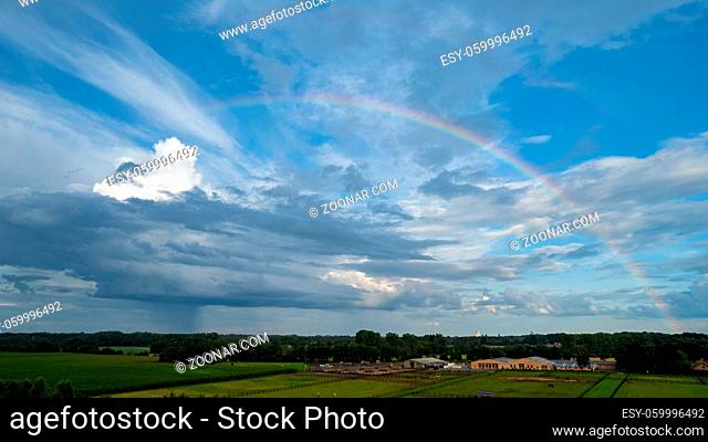 Aerial view shot with drone of a rainbow over stormy sky. Rural landscape with rainbow over dark stormy sky in a countryside at summer day