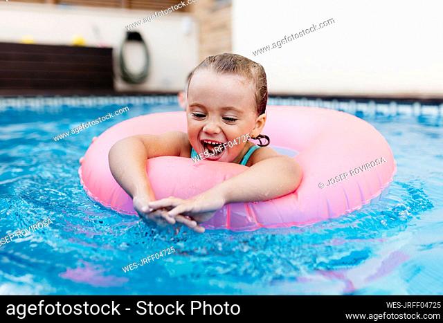Portrait of little girl with floating tire in pool