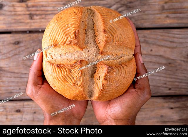 Close up view of hand holding a bread with copy space on wooden surface