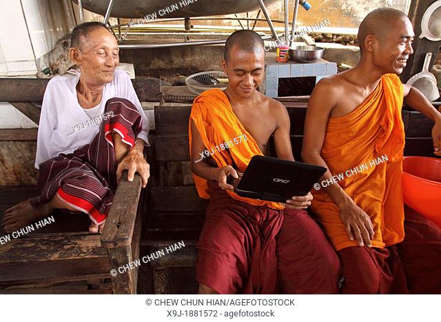 Three monks sitting having a chat and watching movie, , Myanmar, Burma, Asia