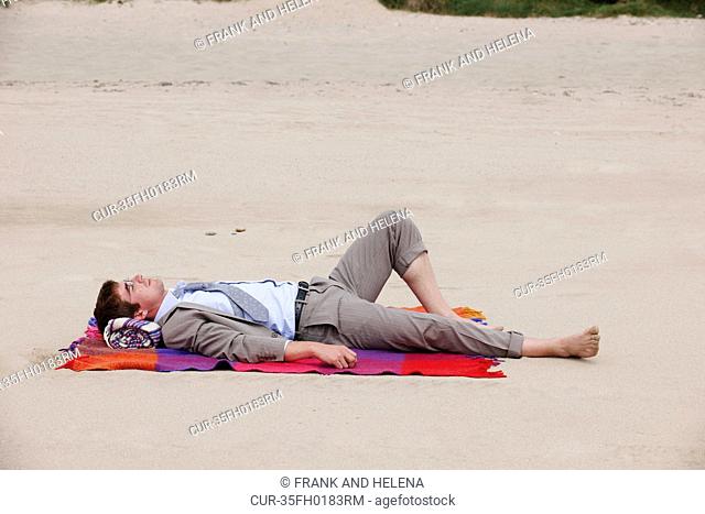 Businessman laying on beach