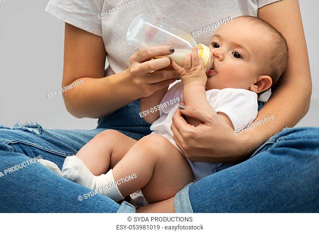 close up of mother feeding baby with milk formula