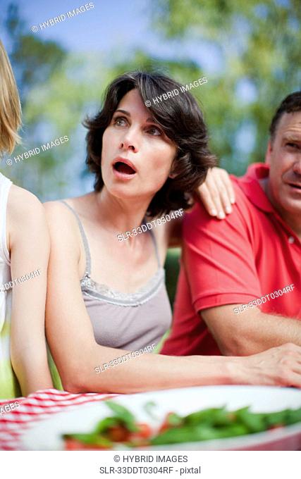 Surprised woman sitting at picnic table