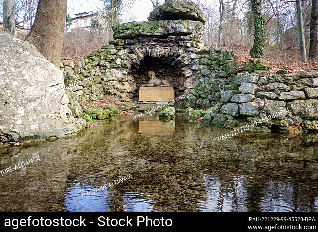 24 December 2022, Thuringia, Weimar: The sphinx resting on a stone cube and the stones surrounding it are reflected by the water surface of the narrow river...