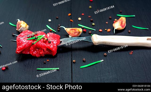 pieces of beef strung on a kitchen fork on a black background, close up