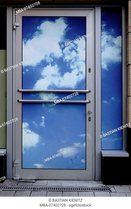 An entrance door with a blue sky and clouds