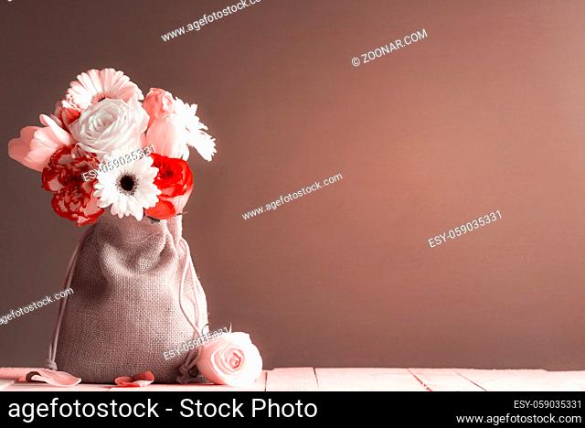 Greeting card with a bouquet of roses, tulips, gerbera, and carnations on a pink wooden table, in a monochrome style