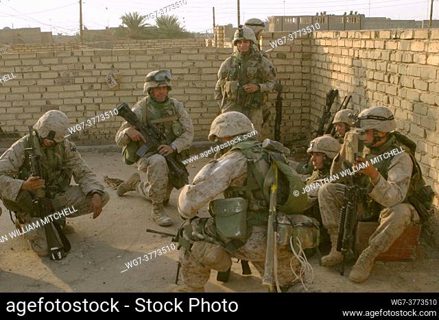 IRAQ Fallujah -- 10 Dec 2004 -- US Marines huddle behind walls as they receive instructions about their next move after a M1A1 tank eliminates the Iraqi...