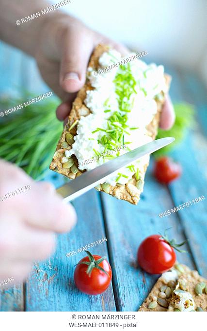 Crispbread, cream cheese, chive, cocktail tomatos and knife, hand