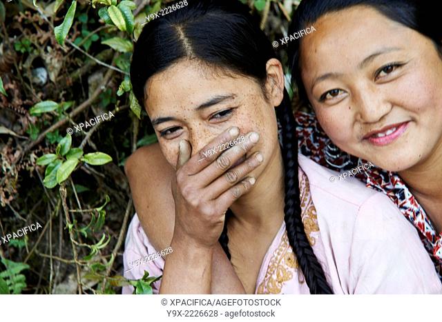 Portrait of two young Tibetan female Labor workers embracing and laughing with each other
