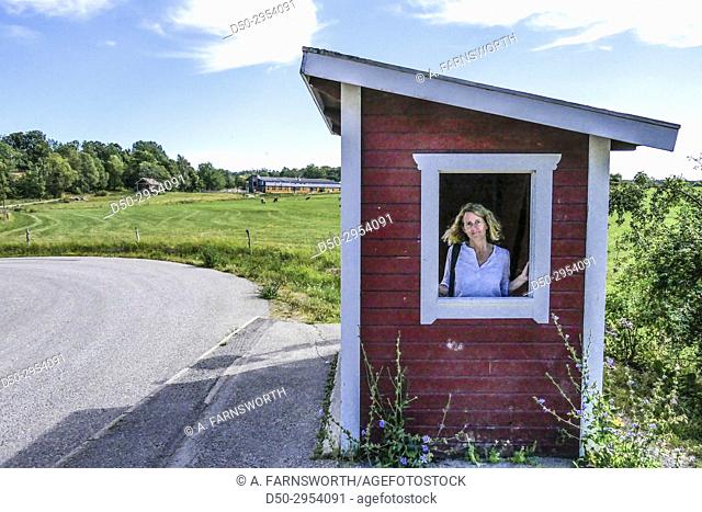 JÄRNA, SWEDEN Saltå Kvarn. Saltå mill and surrounding rural area with fields ecological food store. Portrait of woman at busstop