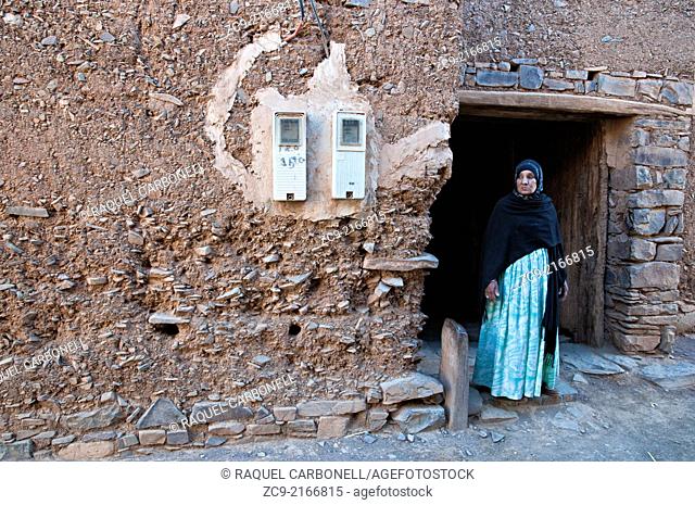 Berber woman at a traditional adobe house doorway in a small village, route between Foum Zguid and Tata, Morocco