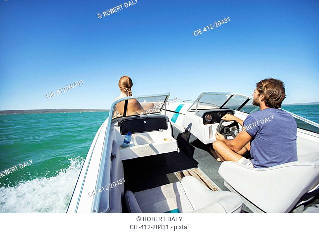 Man steering boat on water with girlfriend