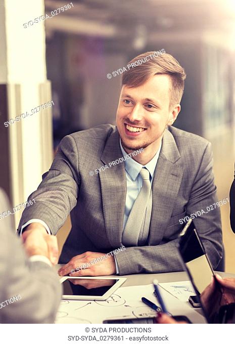 smiling businessman making handshake at office
