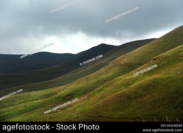 Beautiful Caucasian green landscape of the highlands with a dance of light and shadows on a hillside in cloudy weather