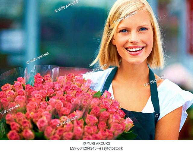 Portrait of a young florist holding a beautiful bunch of blushing pink roses