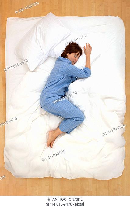 MODEL RELEASED. Mid adult woman lying in bed, asleep