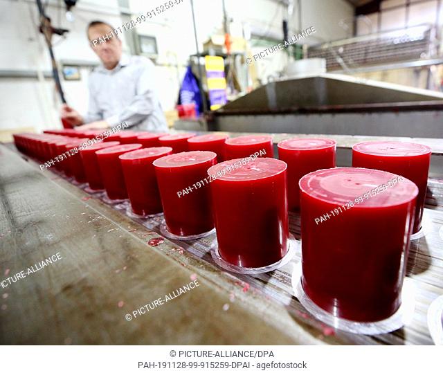 22 November 2019, North Rhine-Westphalia, Kempten: Pillar candles are removed from the special furnace by an employee of the Engels candle manufactory after a...