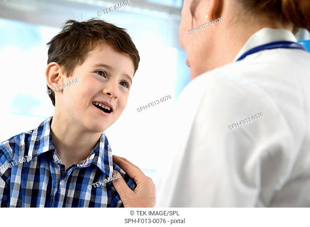 General practice doctor chatting to a 7 year old boy during a consultation in a clinic