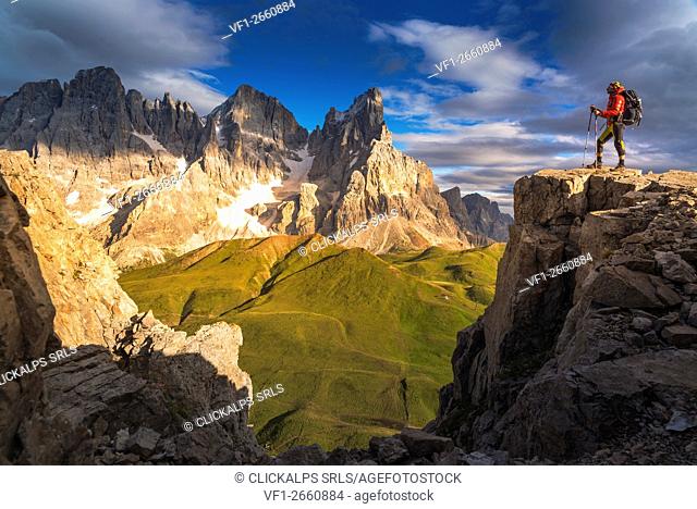 Hiker standing on the top of Castellazzo Mount near Passo Rolle. Pale di San Martino range with the famous Cimon della Pala (the peak in the center) in...