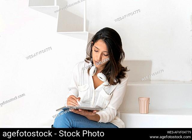 Portrait of young architect sitting on steps in a studio working on tablet