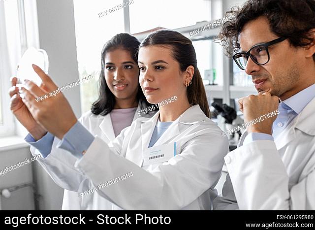 group of scientists with petri dish in laboratory