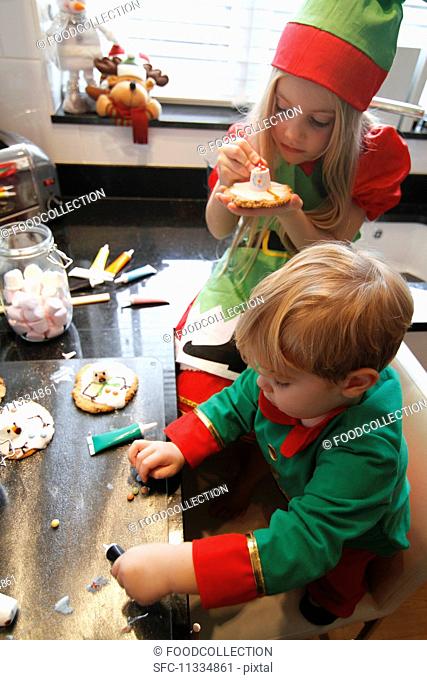 Children decorating Christmas biscuits in a kitchen
