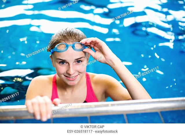 Female swimmer in an indoor swimming pool - looking at the camera, smiling wholeheartedly (shallow DOF; color toned image)