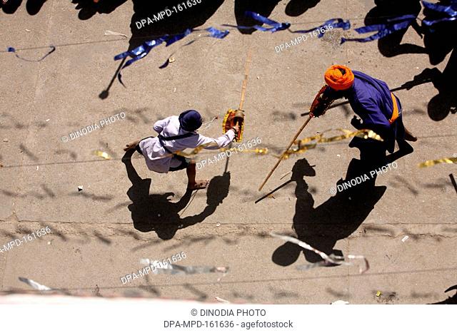 Nihang or Sikh warriors performing stunts with wooden swords in during Hola Mohalla celebrations at Anandpur sahib in Rupnagar district ; Punjab ; India