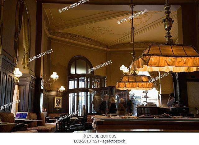 Mariahilf District Cafe Sperl the preferred cafe of Adolf Hitler. Interior with customers in blur of movement at entrance and young woman using laptop in window...