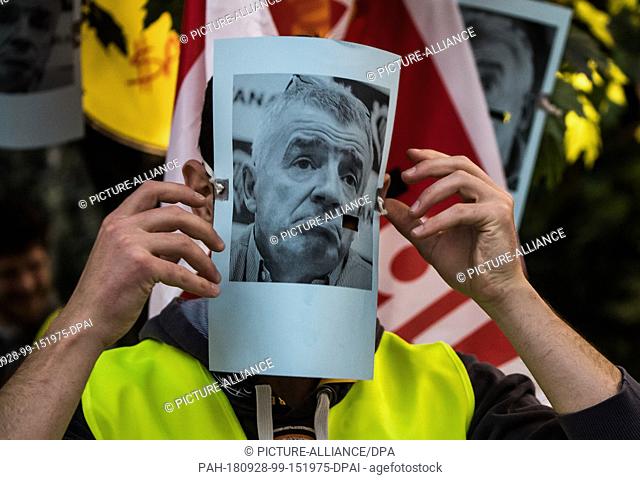 28 September 2018, Hessen, Frankfurt-Main: A striking flight attendant puts on a mask showing the portrait of Michael Kevin O'Leary, Chairman of Ryanair