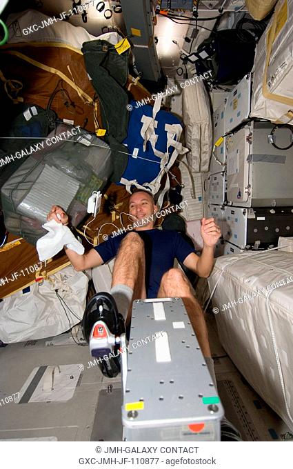 Astronaut Randy Bresnik, STS-129 mission specialist, exercises on a bicycle ergometer on the middeck of Space Shuttle Atlantis during flight day three...