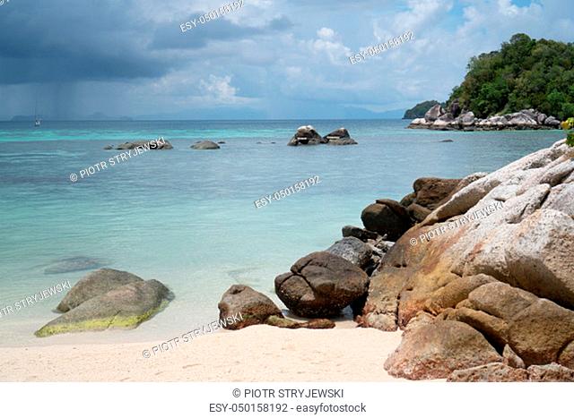 Sandy beach with rocks over sea and cloudy sky. Koh Lipe island in Thailand