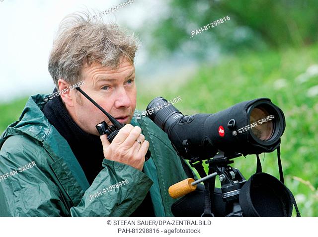 Guenter Nowald, leader of the crane information centre in Gross Mohrdorf, observes cranes in a field near Velgast, Germany, 16 June 2016