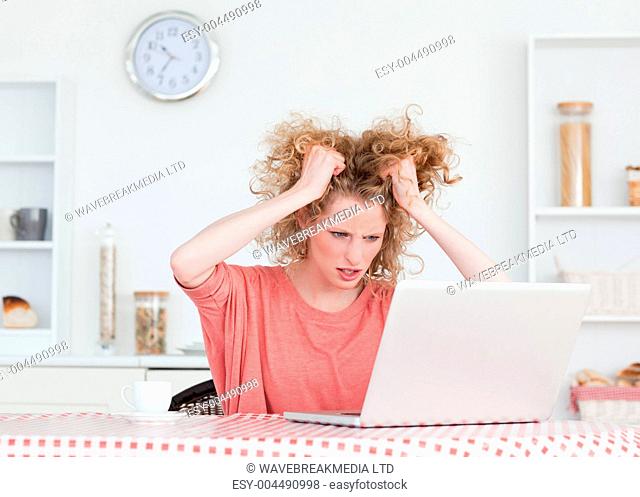 Upset blonde female relaxing with her laptop while sitting in th