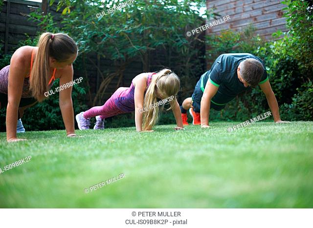 Family exercising in garden, doing push-ups