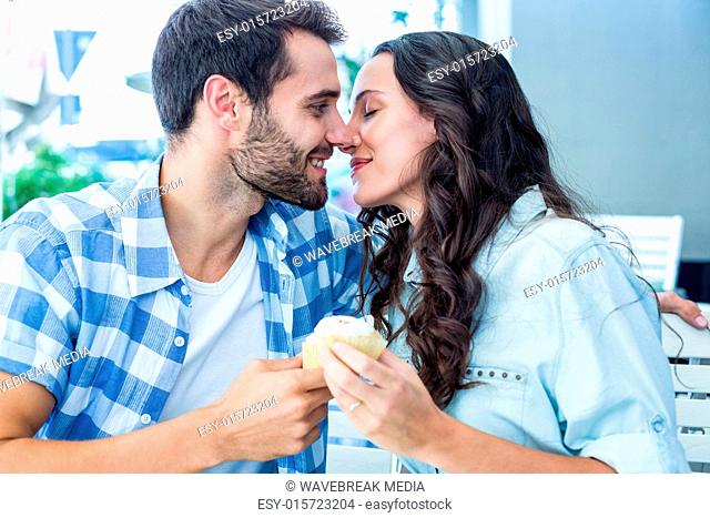 Couple kissing while holding cupcakes