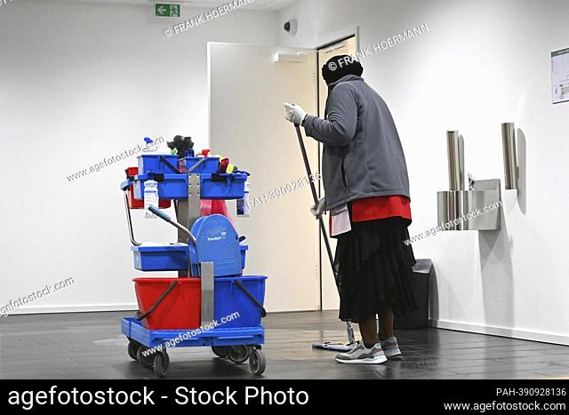 Cleaner at work with cleaning trolley, dark-skinned, colored cleaning lady, cleaning, minimum wage, , working hours, wages, dumping wages, marginally employed