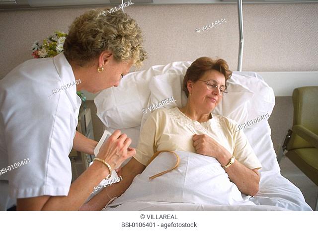 ELDERLY HOSP. PATIENT WITH NURSE<BR>Reconstructed scene. Model and nurse.<BR>Placing an IV drip