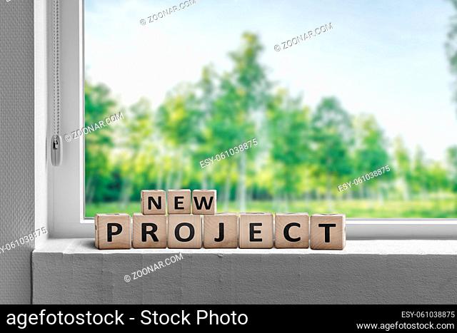 New project sign in a window sill with green trees in the garden