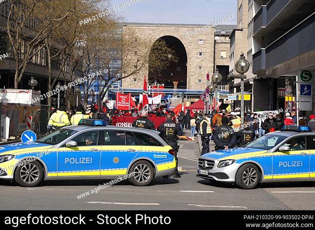 20 March 2021, Baden-Wuerttemberg, Stuttgart: Police cars stand in front of the main station, from where the participants of a demonstration move through the...