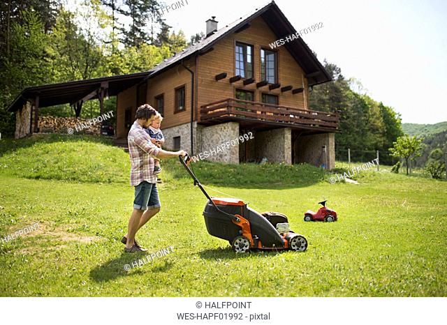 Father with his little son mowing the lawn