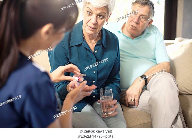 Nurse giving medication to senior woman at home