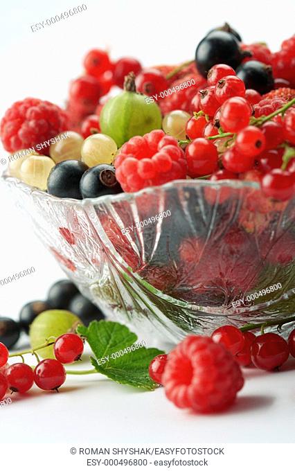 Mixed summer splitted berries in a cristal bowl on white