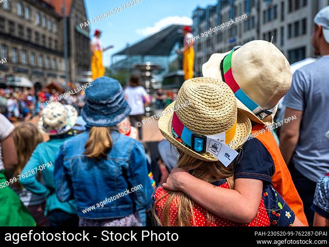 20 May 2023, Saxony, Chemnitz: Visitors wearing hats watch a performance by the Circus Firemen at the 6th Hat Festival in downtown Chemnitz