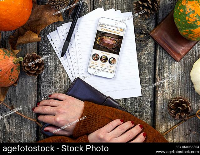 Touchscreen smartphone with online cooking blog on the screen at rustic table in the kitchen. Thanksgiving recipe. Autumn concept cooking