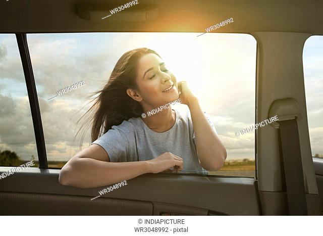 Woman with windblown hair enjoying sun outside of car