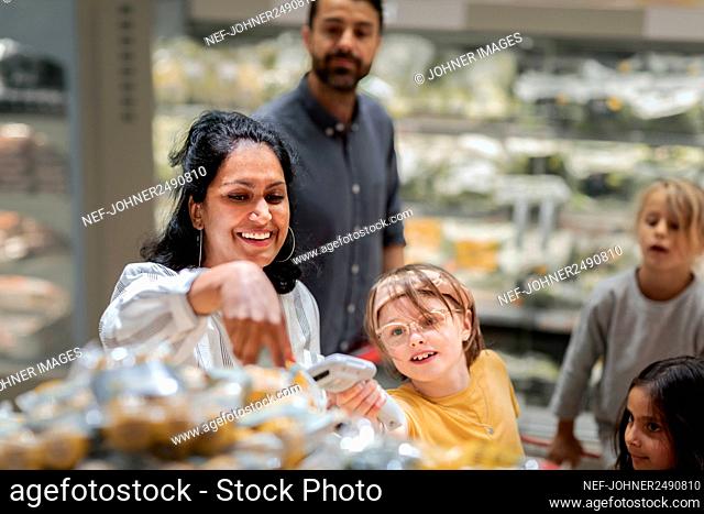 Girl with mother scanning item in supermarket