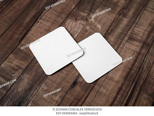 Two blank white beer coasters on vintage wooden background. Responsive design mockup